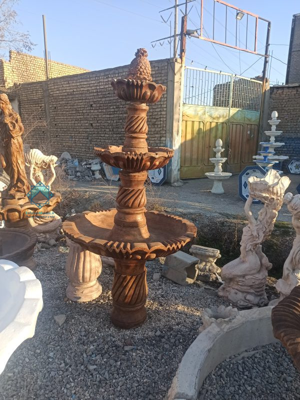 تصویر آبنمای مسی رنگ در کنار چند تندیس با رنگ سفید
