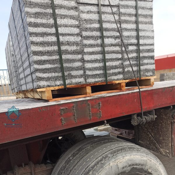 پالت‌های بسته‌بندی شده جدول‌های سنگی و سنگ‌های حجمی گرانیت روی کامیون، آماده برای حمل و نقل در پروژه‌های ساختمانی