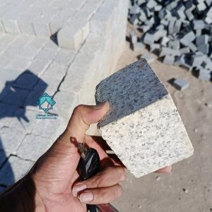 سنگ کوبیک گرانیت خاکستری در دست یک فرد برای نمایش ضخامت جهت راهنمایی خرید سنگ کوبیک گرانیت مشکی